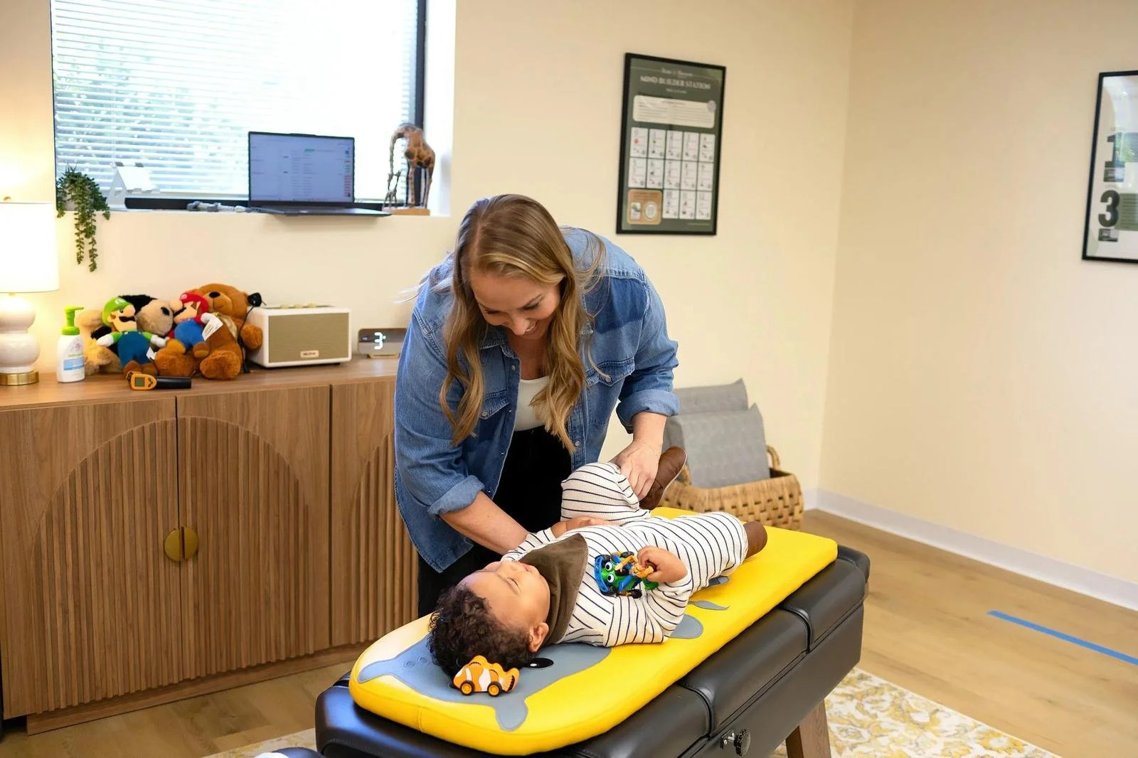Dr. Jennifer Gordon gently checking a toddler’s leg while the child lies on a pediatric chiropractic table