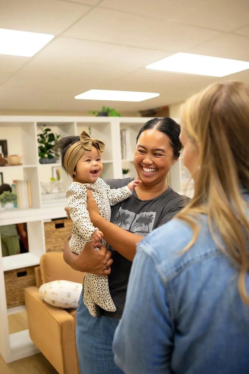 Mother holding her smiling baby while talking with Dr. Jennifer Gordon