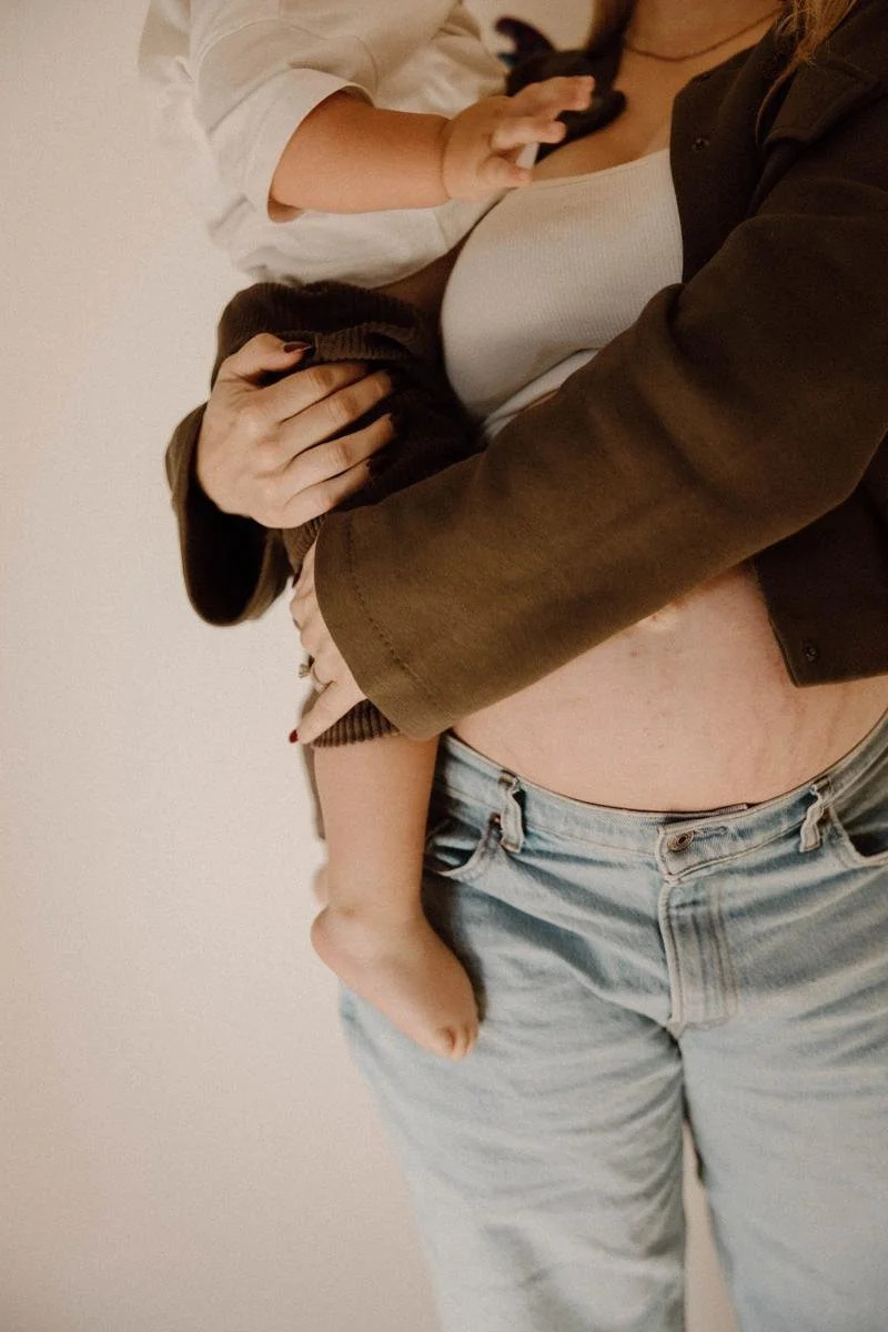 Pregnant mother holding her toddler with her baby bump visible