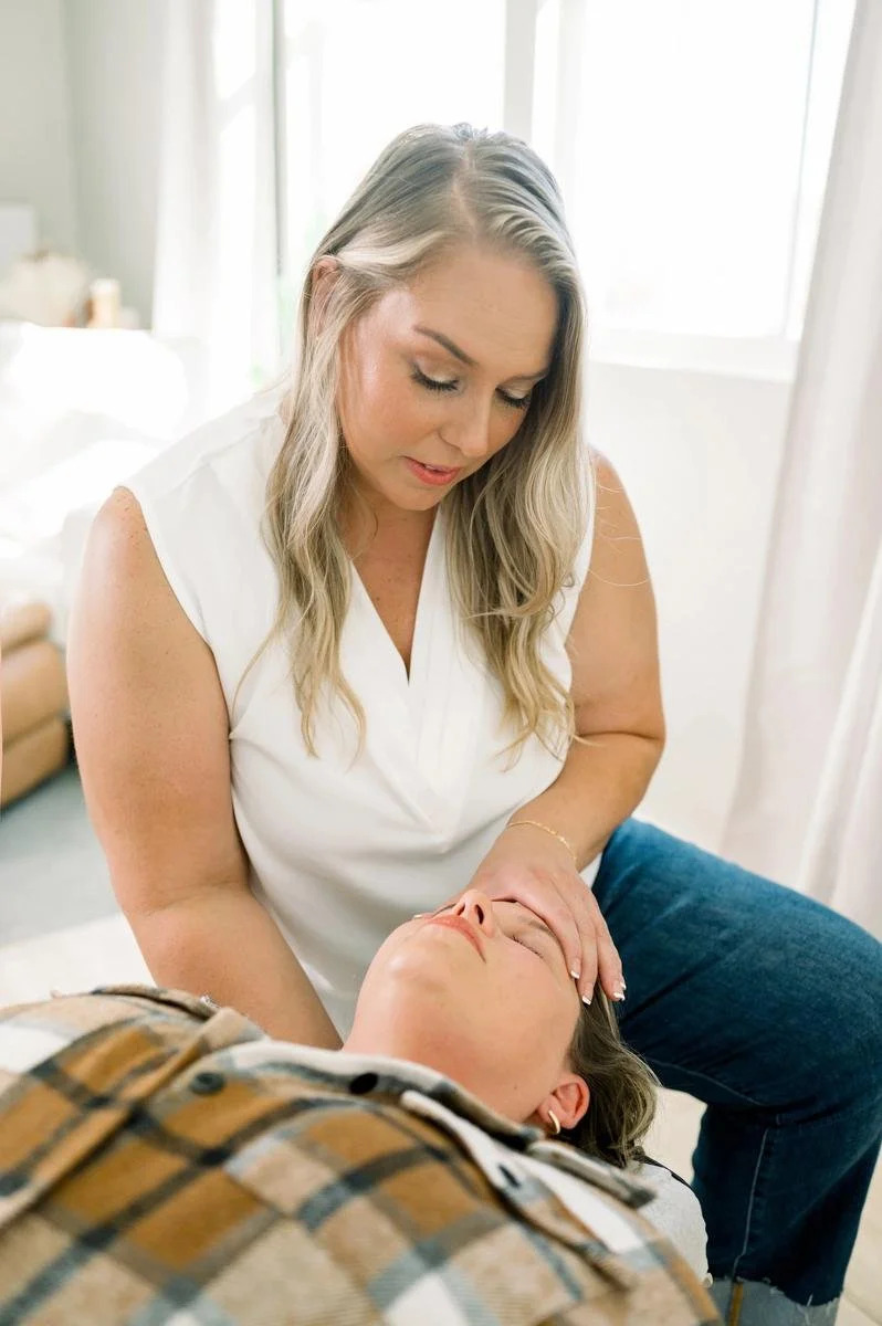 Dr. Jennifer Gordon gently adjusting the neck of an adult woman lying face up