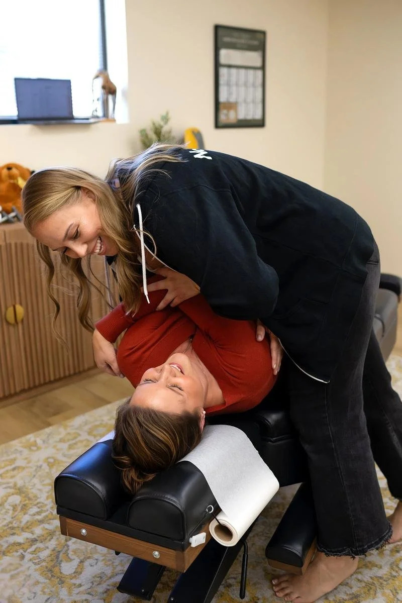 Dr. Jennifer Gordon performing a side-lying pelvic adjustment on an adult woman in a red shirt
