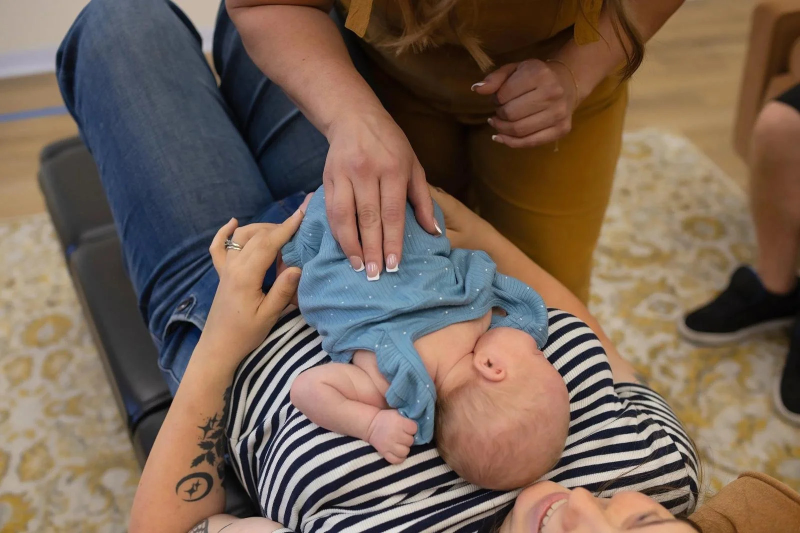 Chiropractor gently adjusting an infant resting on a parent’s chest