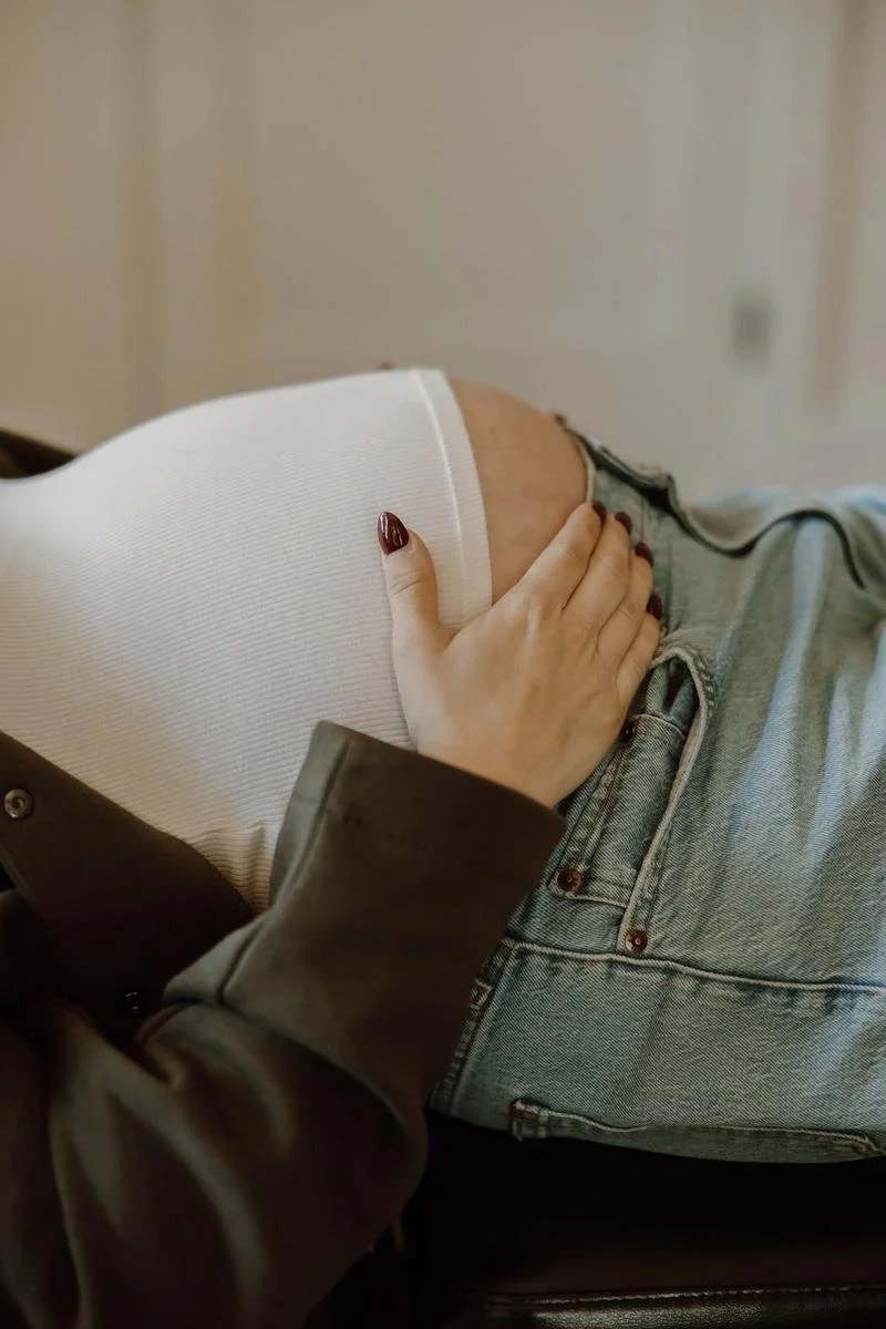 Close-up of a pregnant patient reclining with one hand resting on her baby bump