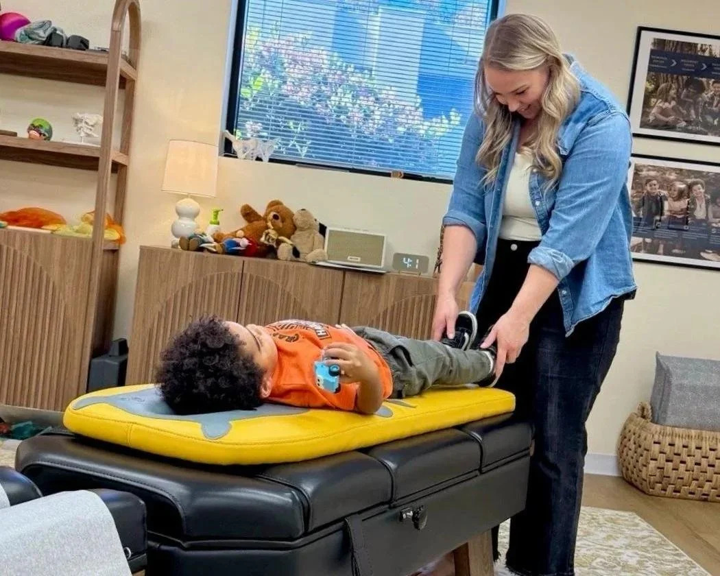 Dr. Jennifer Gordon gently holding the ankles of a toddler lying face up on a treatment table